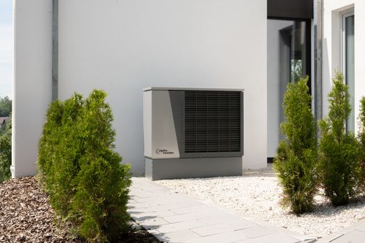 Buitenunit van een warmtepomp naast een Nederlandse woning met vloerverwarming en goede isolatie