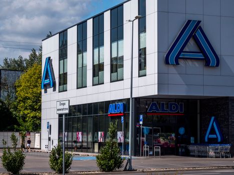 Voorkant van een Aldi-supermarkt met winkelwagens en aanbiedingen bij de entree