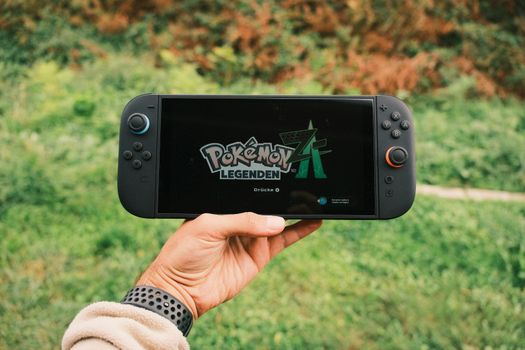 Nintendo Switch 2 op een salontafel naast een tv, controller en handheld-scherm in moderne woonkamer