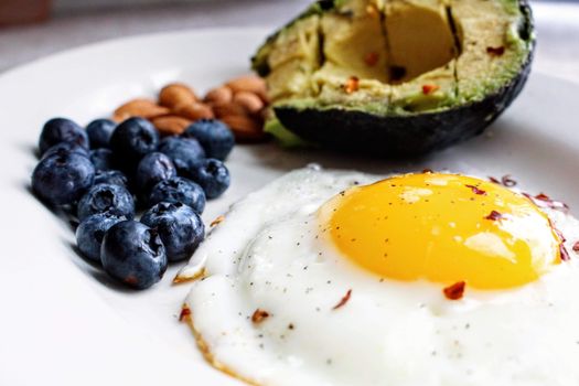 Vrouw bekijkt keto boodschappen in de supermarkt met avocado, eieren en groenten in haar mandje